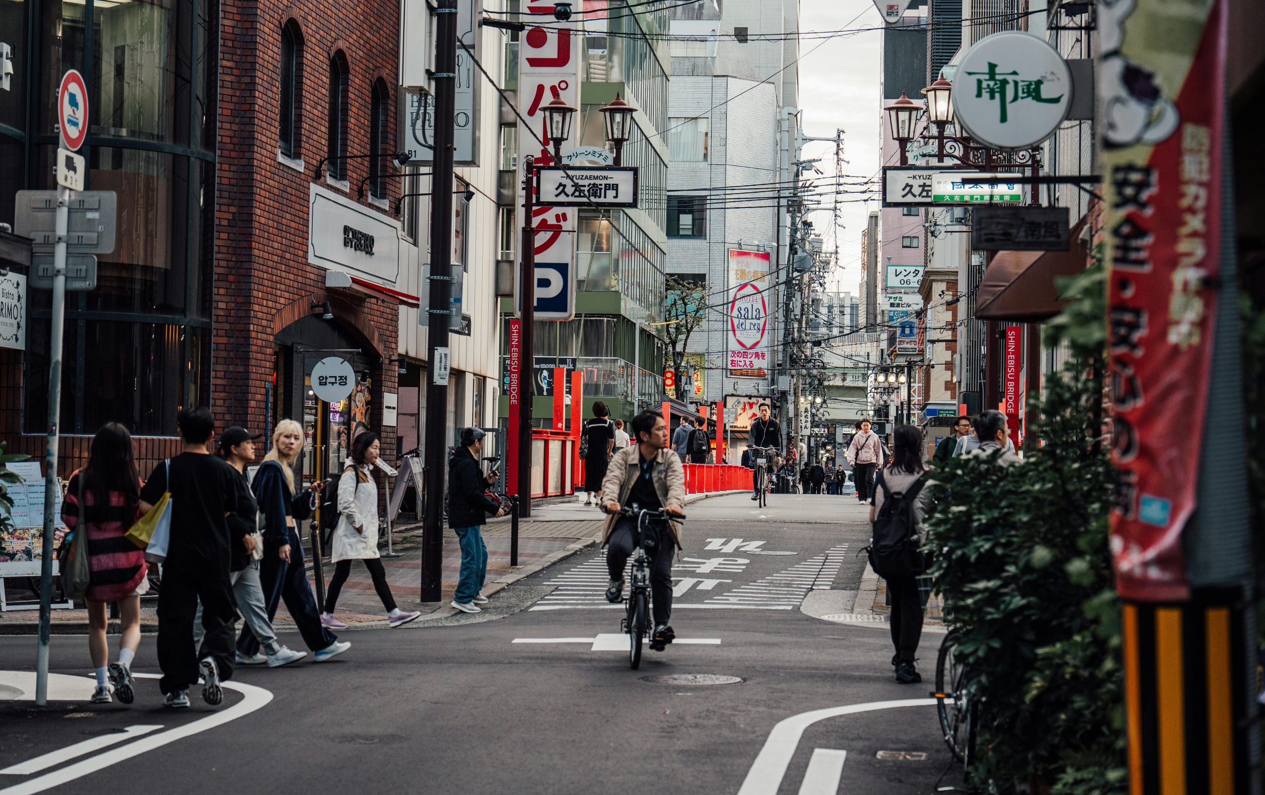 A vibrant street in Osaka featuring pedestrians and cyclists amidst urban architecture.
